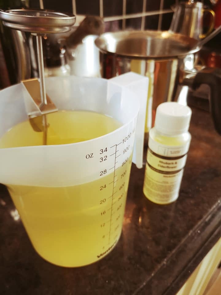 Melted soy wax in a pouring jug with a fragrance oil bottle, ready to be hand-poured into candles